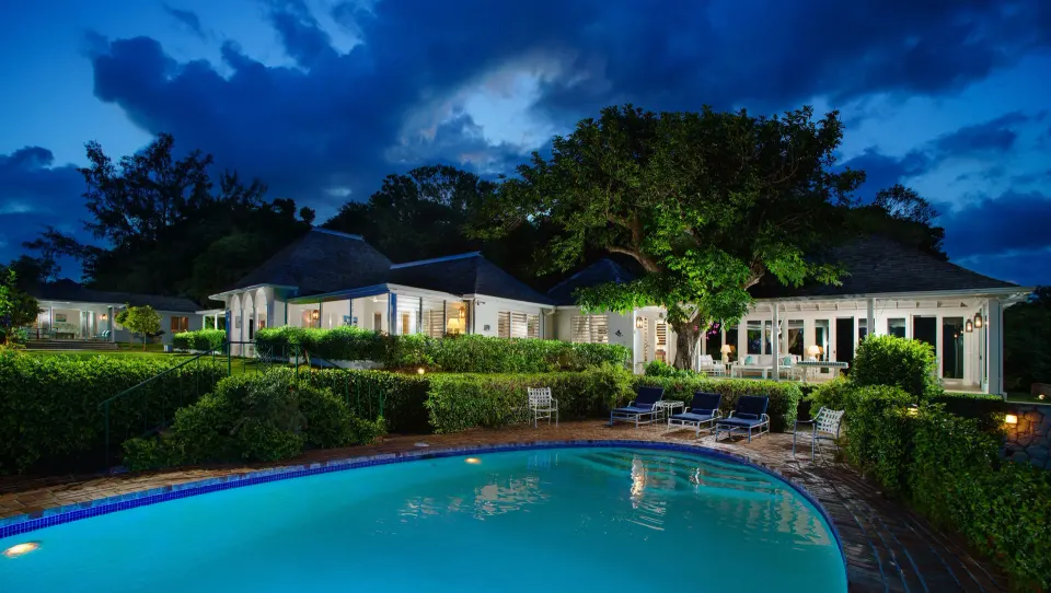 Classic Villa exterior with illuminated private pool at dusk at Round Hill Hotel And Villas.