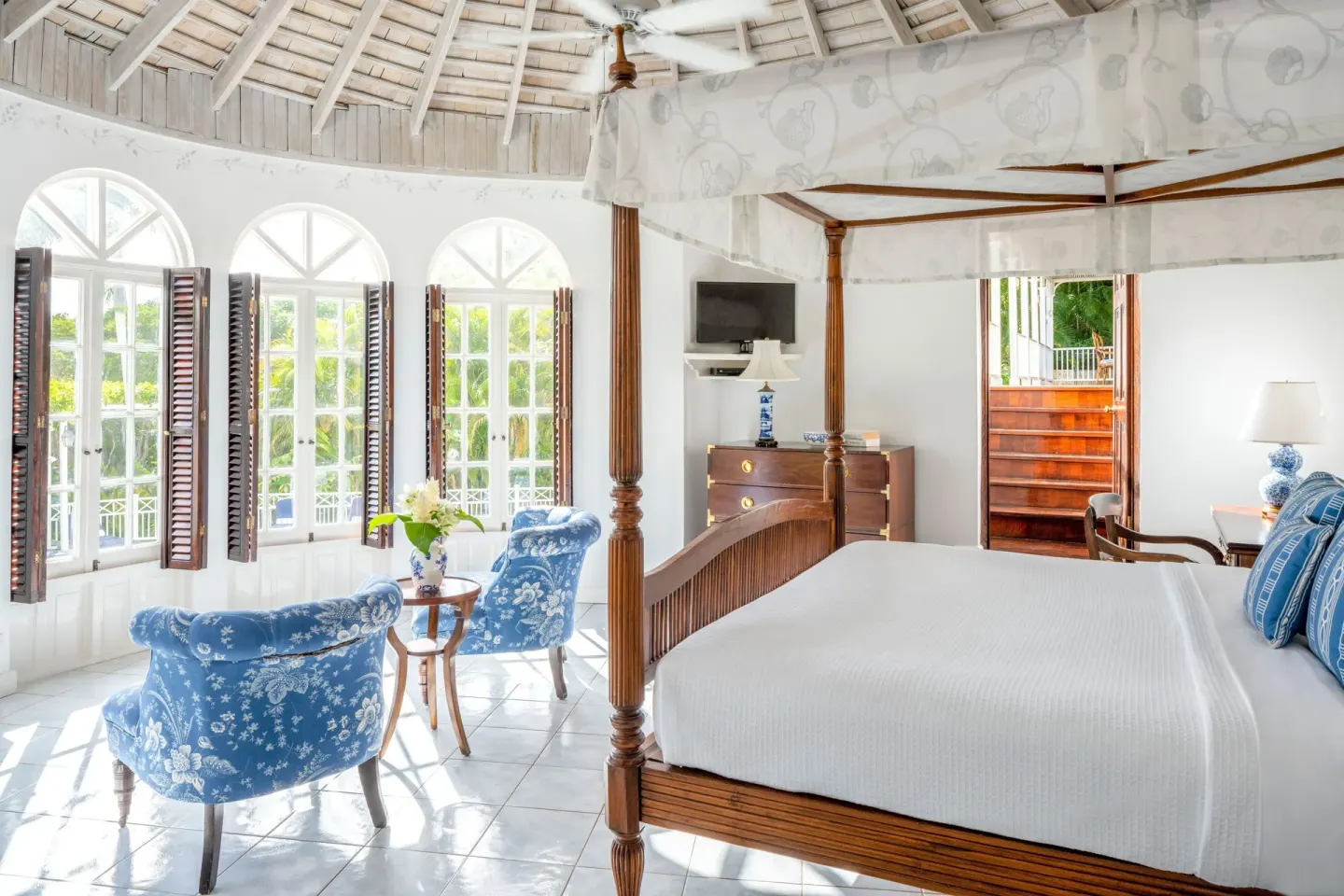 Four-poster bed and blue chairs in a classic villa bedroom at Round Hill Hotel And Villas.