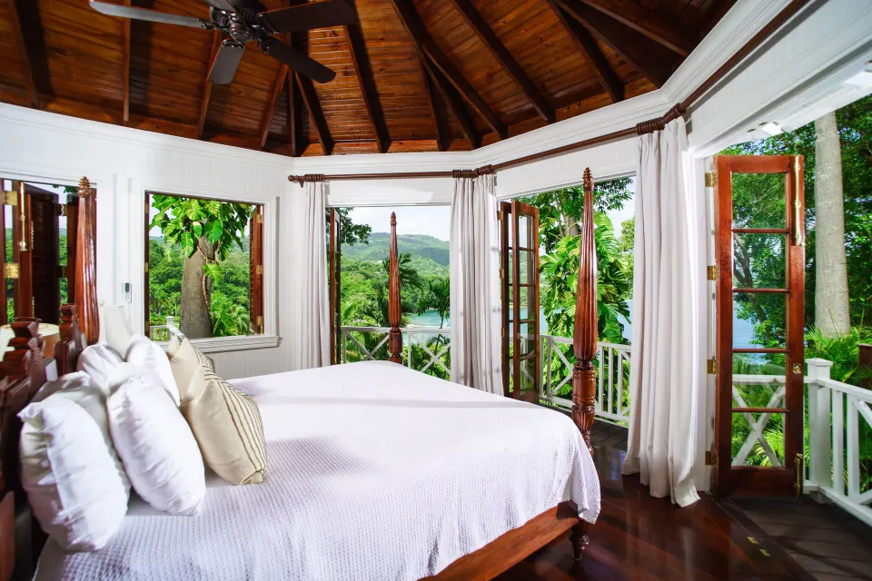 Four-poster bed with open balcony doors at Round Hill Hotel And Villas.