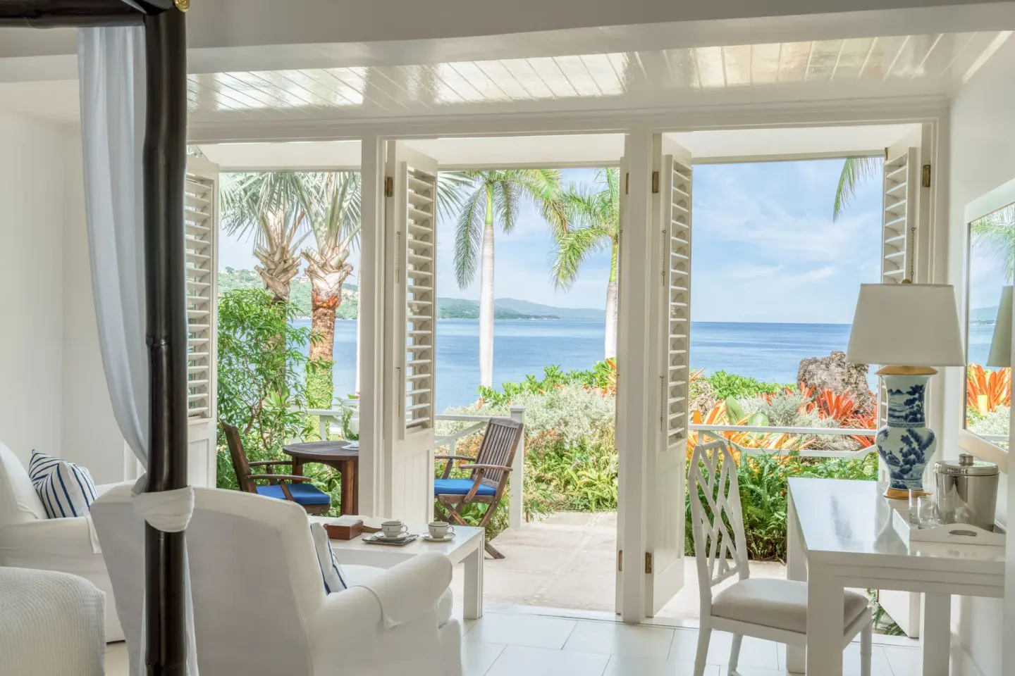 Oceanfront Premium Room with canopy bed and open balcony doors at Round Hill Hotel And Villas.