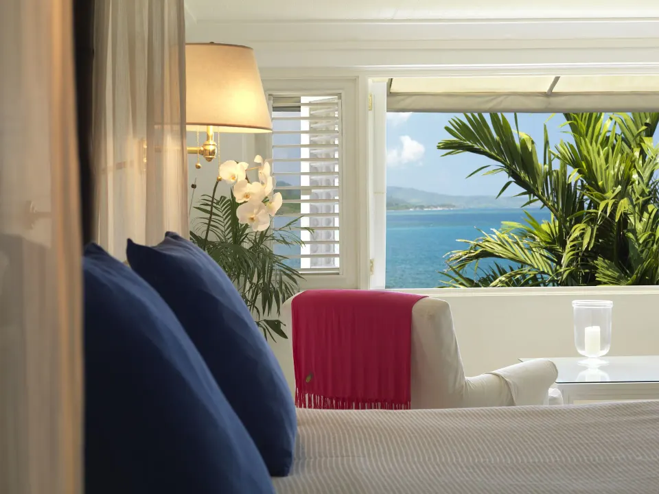 Premium Room Ocean View bed with armchair and coastal view at Round Hill Hotel And Villas.