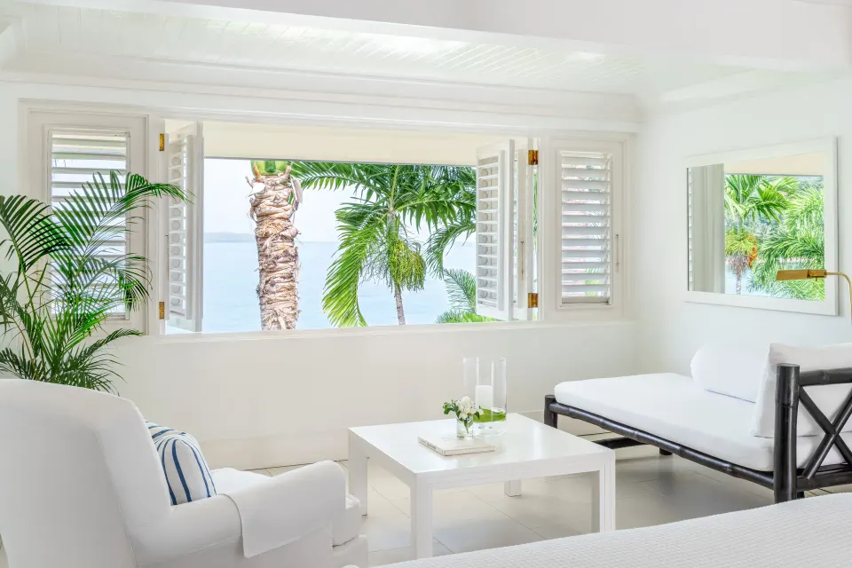 Premium Room Ocean View lounge area with daybed and palm view at Round Hill Hotel And Villas.