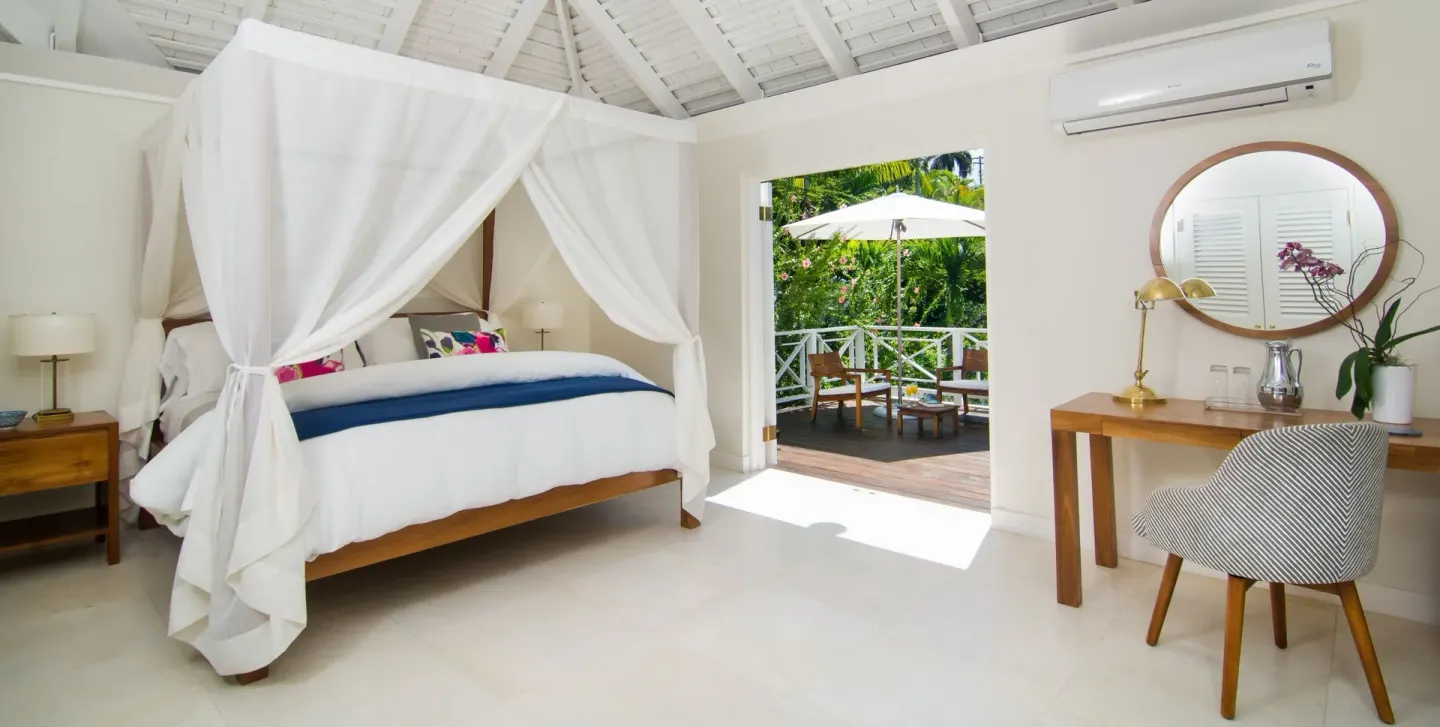 Canopy bed and open terrace in a Signature Villa bedroom at Round Hill Hotel And Villas.
