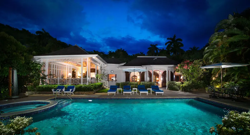 Private pool and illuminated Signature Villa at Round Hill Hotel And Villas at dusk.