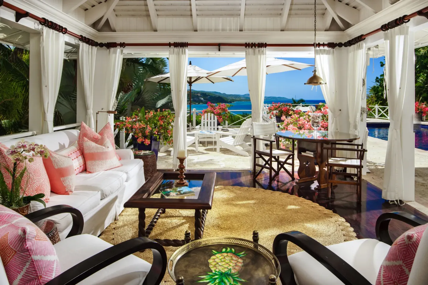 Open-air living room in the Signature Villa at Round Hill Hotel And Villas with ocean views and pink accents.