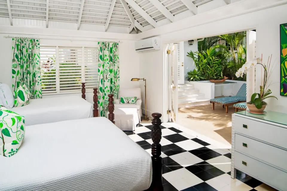 Twin bed guest room in the Signature Villa at Round Hill Hotel And Villas with green prints and terrace access.
