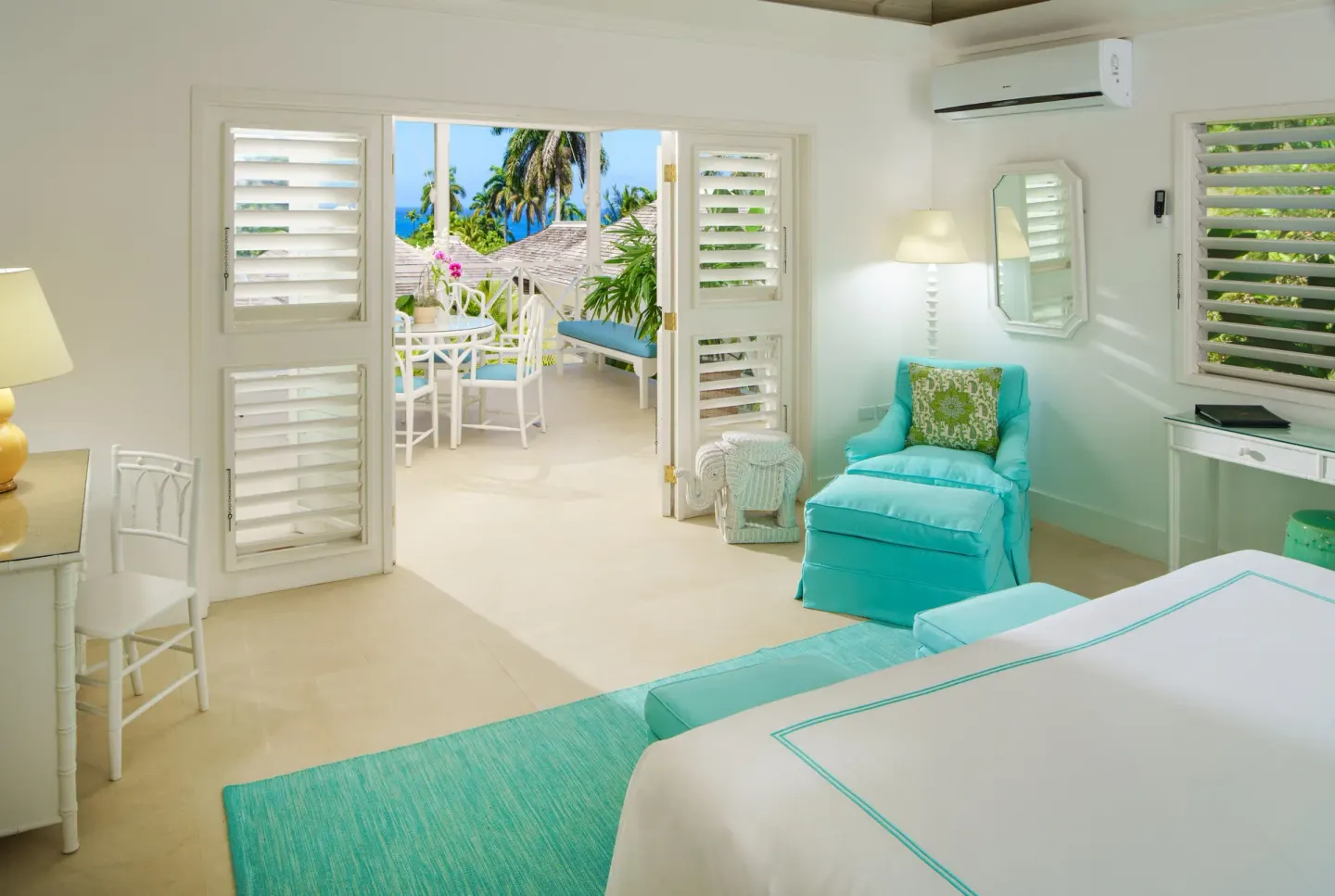 Guest room with turquoise accents and terrace at Round Hill Hotel And Villas.