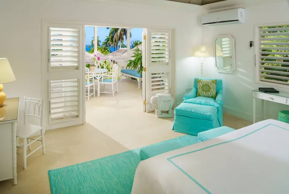 Guest room with turquoise accents and terrace at Round Hill Hotel And Villas.