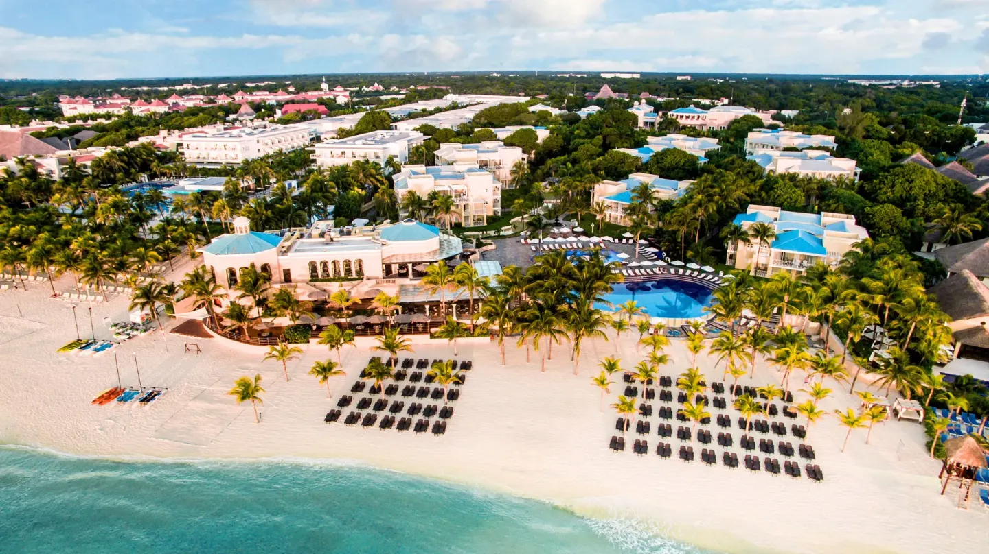 Aerial view of Royal Hideaway Playacar beach, pool, palms, and lounge chairs along the sand.