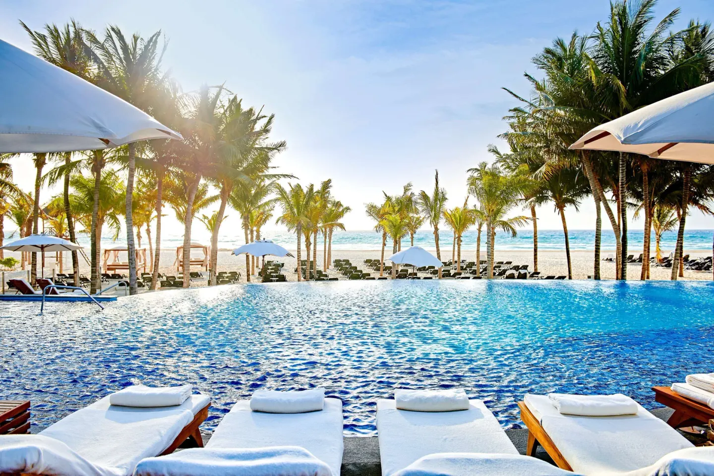 Infinity-style pool facing the beach and palms at Royal Hideaway Playacar.
