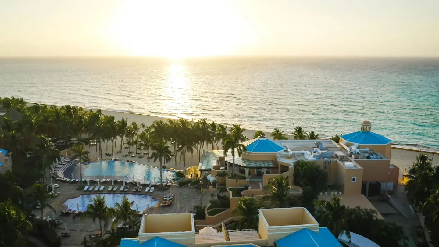 Sunset over the beach, pools, and palm-lined grounds at Royal Hideaway Playacar.