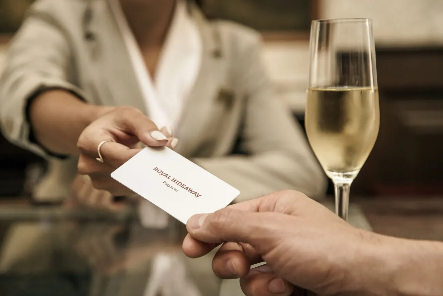 Guest receives a room key beside a champagne flute at Royal Hideaway Playacar.