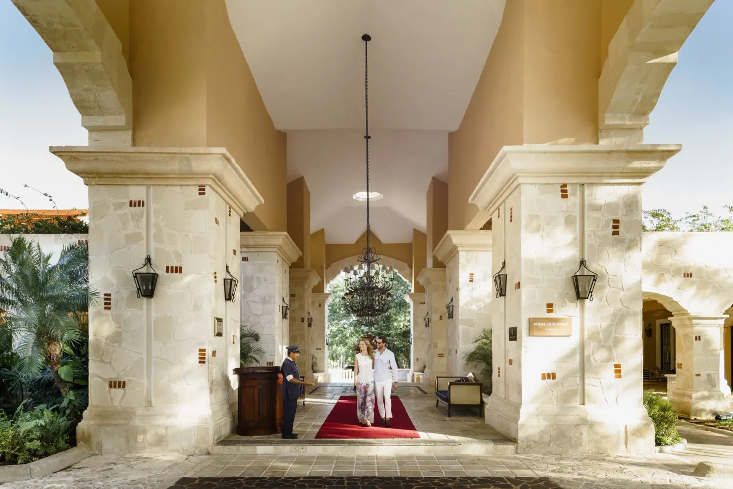 Covered stone entrance with red carpet and arriving guests at Royal Hideaway Playacar.