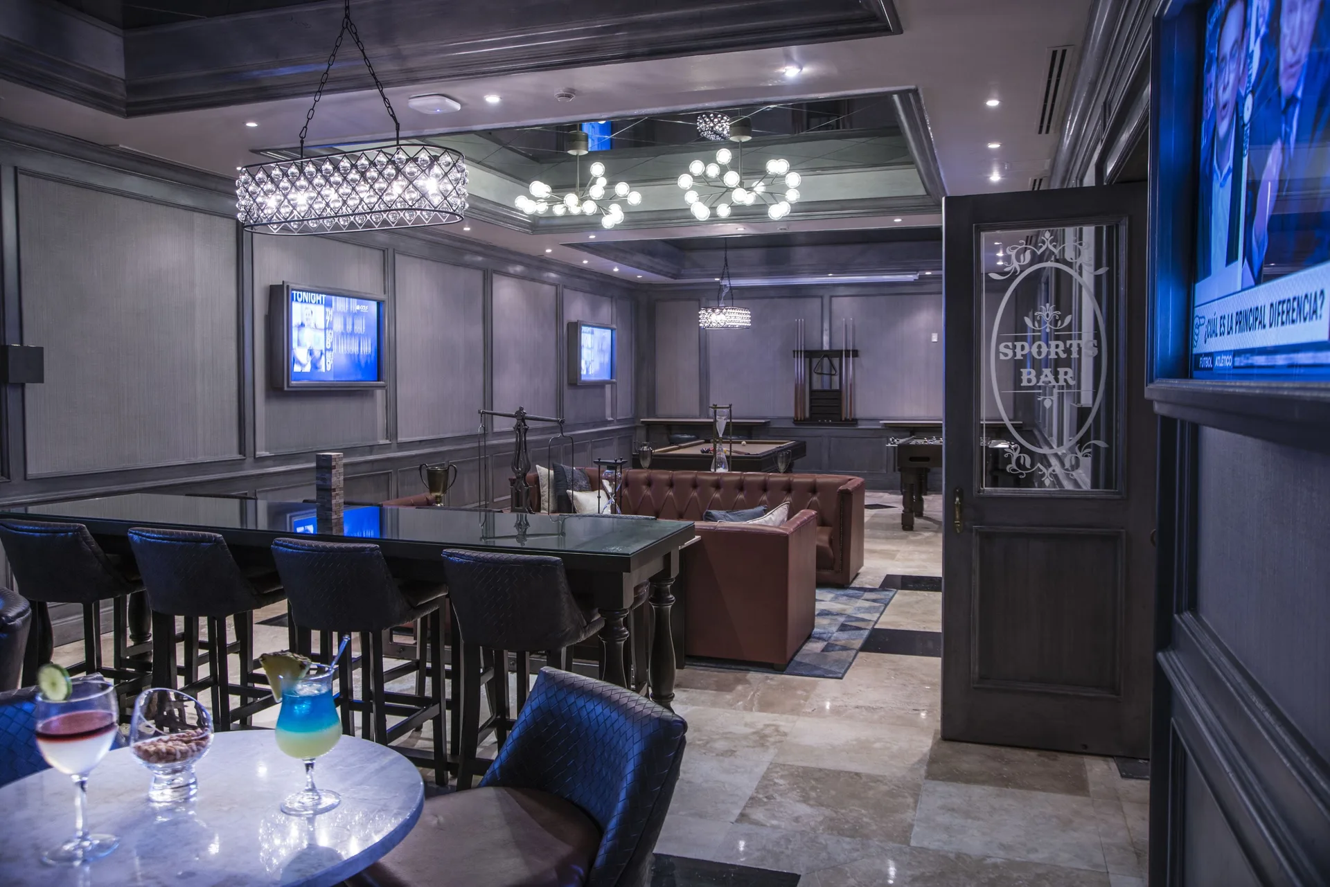 Sports bar with televisions, lounge seating, and game tables at Royal Hideaway Playacar.