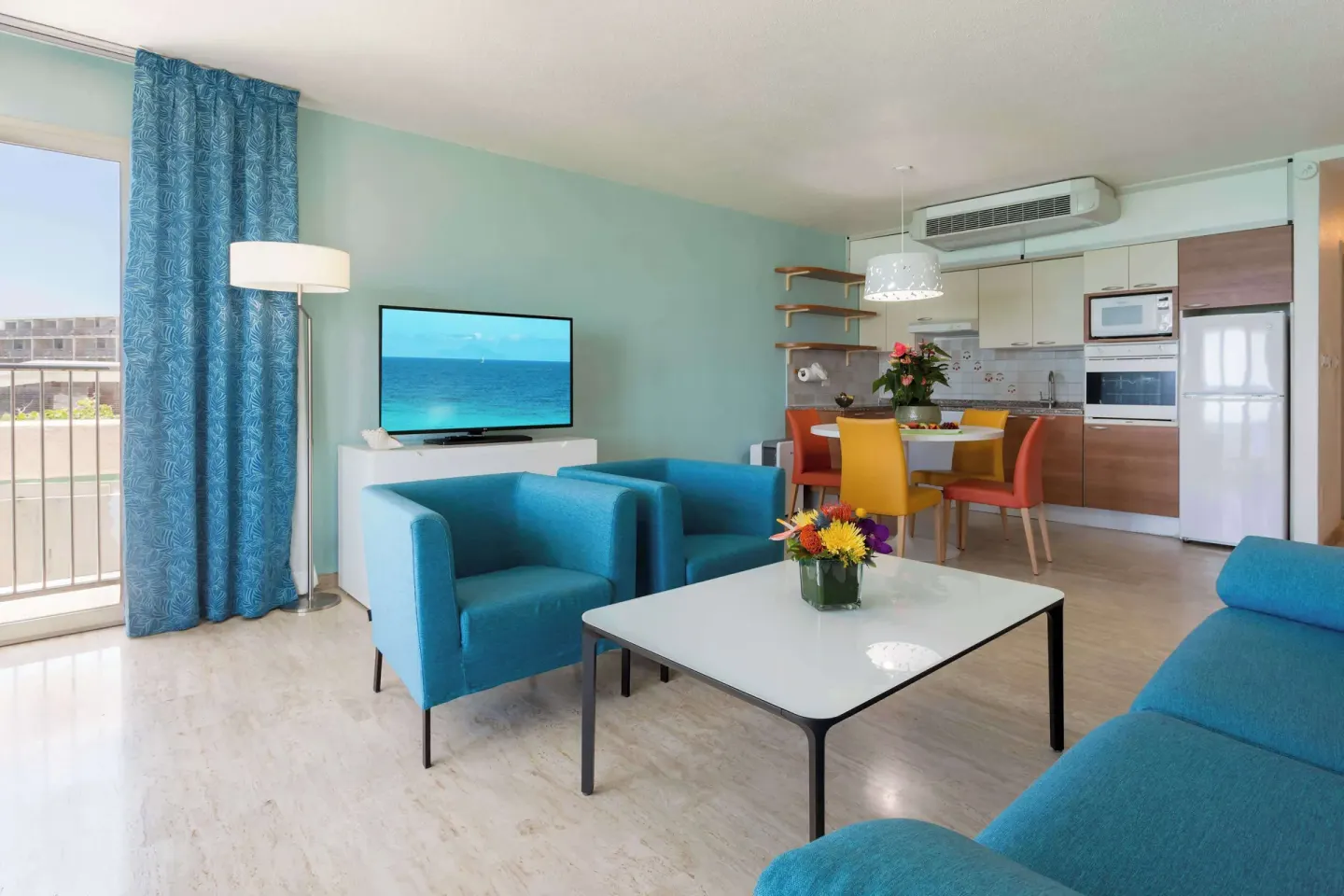 Blue-accent living room with balcony and kitchen at Royal Islander Resort La Plage.
