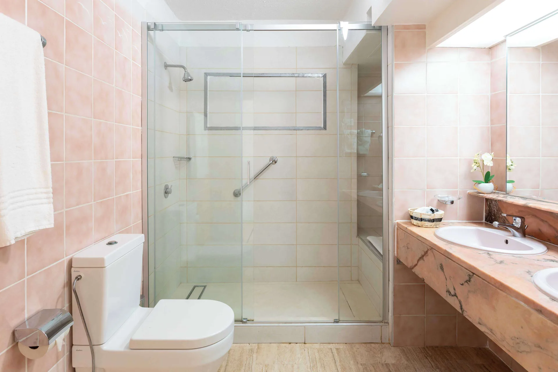 Bathroom with glass walk-in shower and pink tile at Royal Islander Resort La Plage.