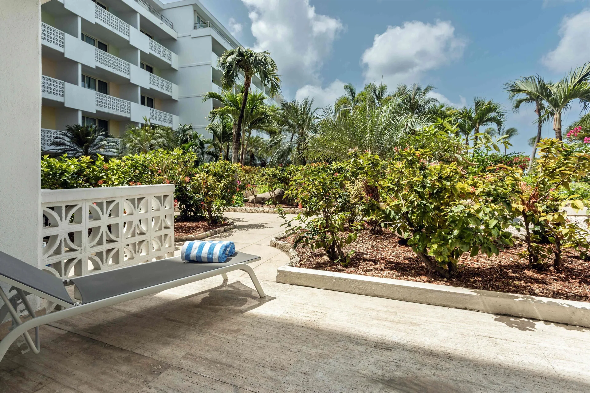 Patio lounge chair beside tropical gardens at Royal Islander Resort La Plage.