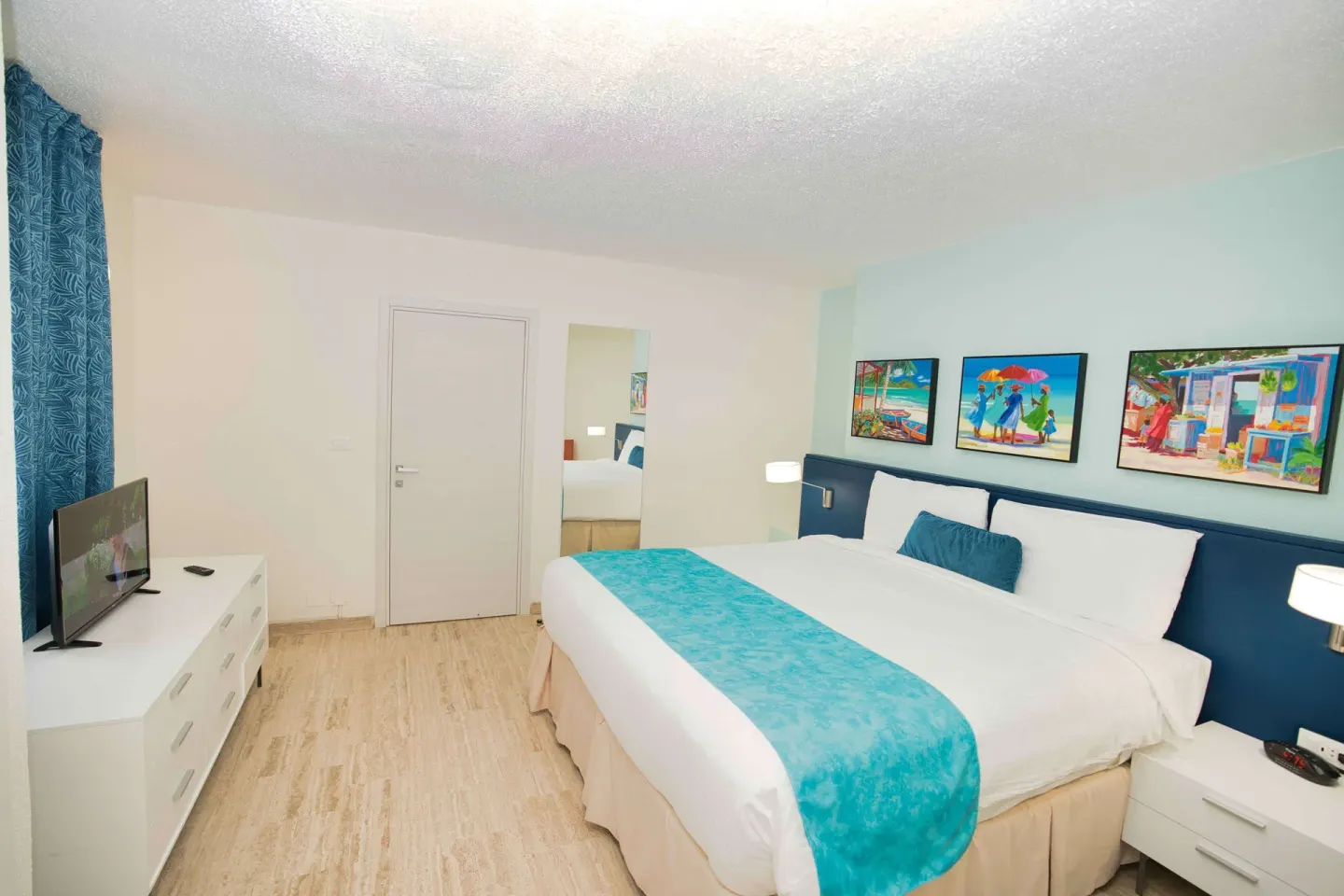 Guest bedroom with king bed and turquoise runner at Royal Islander Resort La Plage.