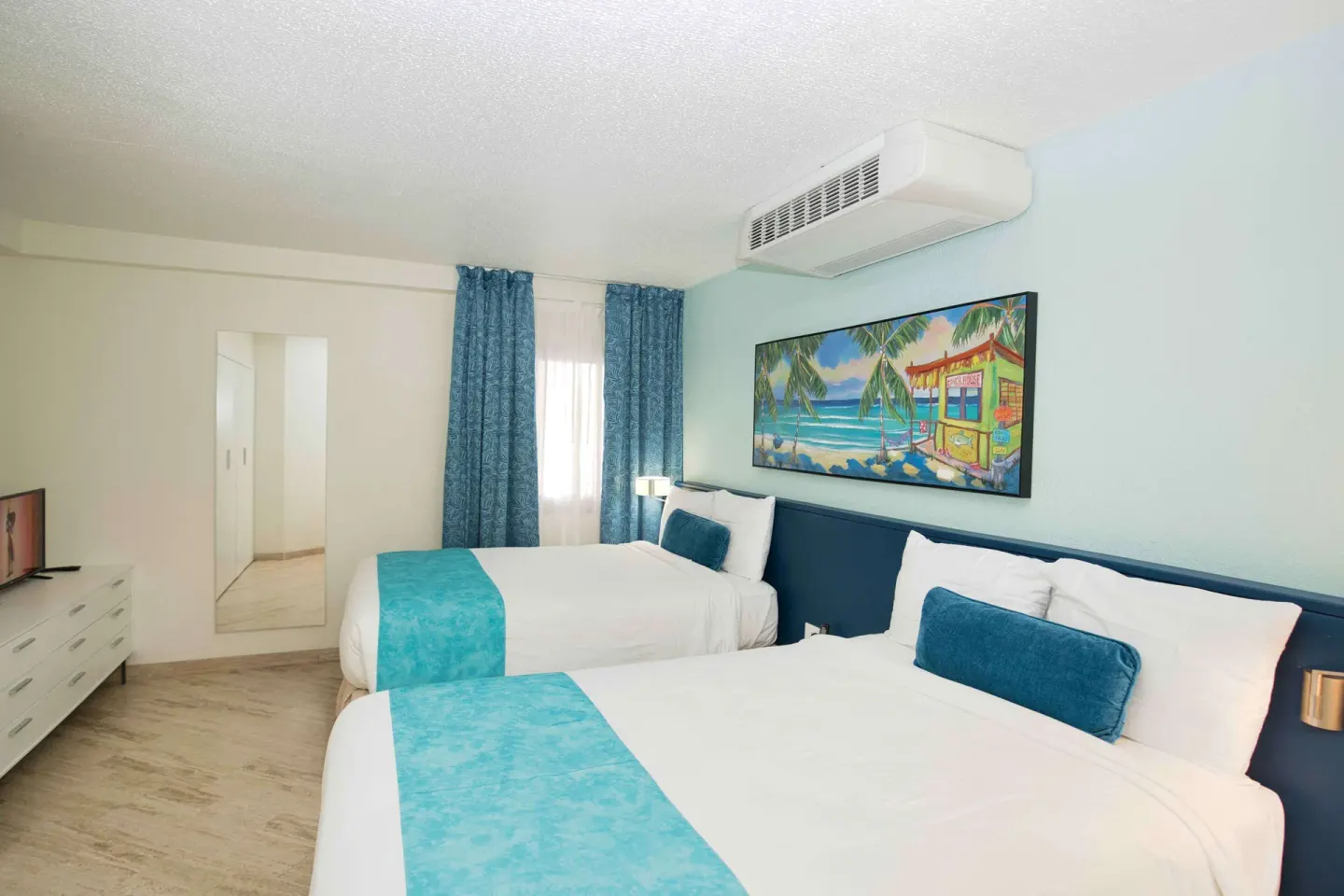 Guest bedroom with two beds and turquoise accents at Royal Islander Resort La Plage.