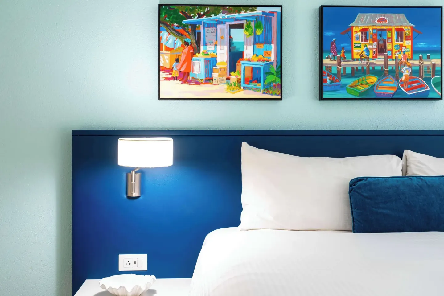 Close-up of a bed with blue headboard and colorful art at Royal Islander Resort La Plage.