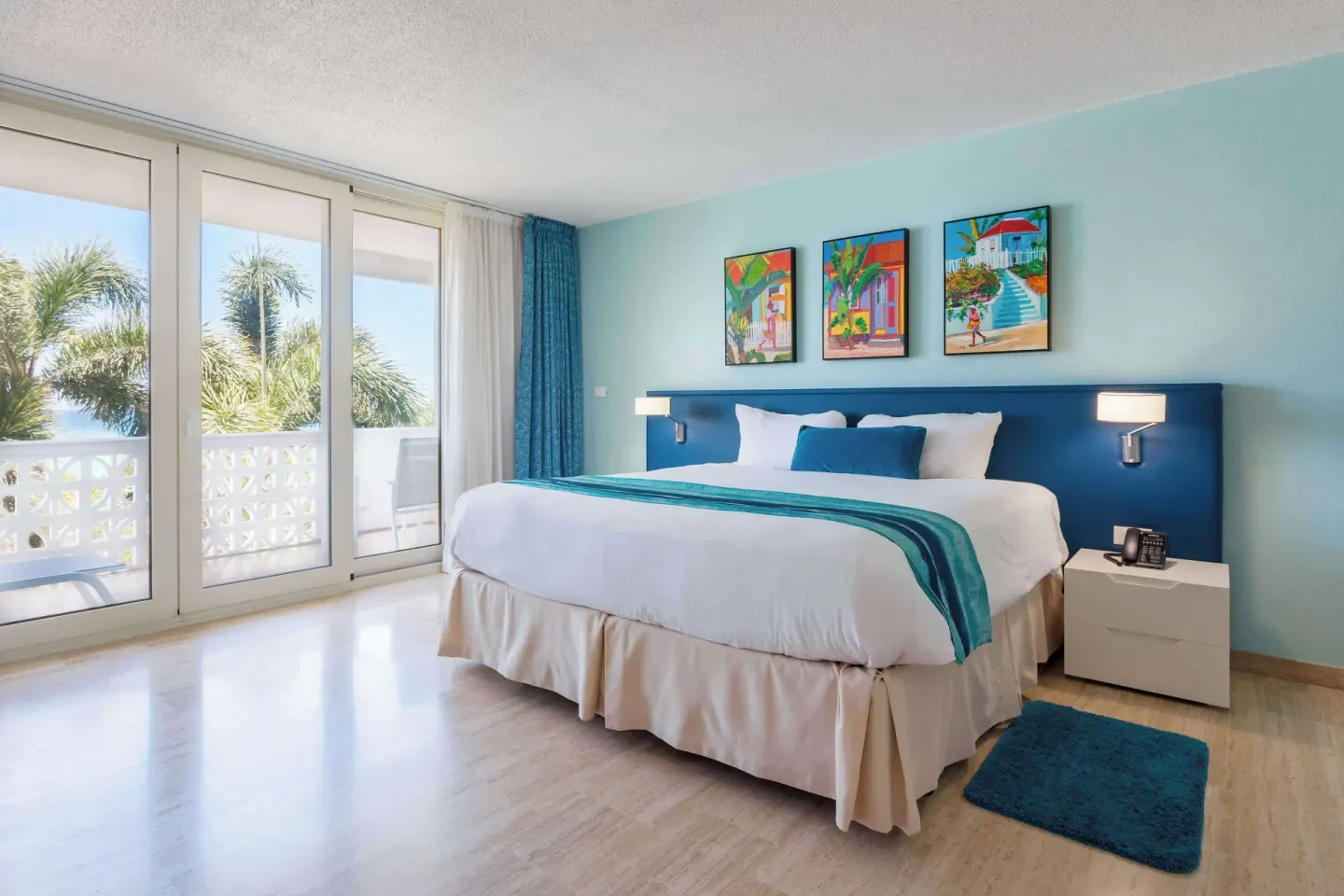 King bed room with balcony doors and palm trees at Royal Islander Resort La Plage.