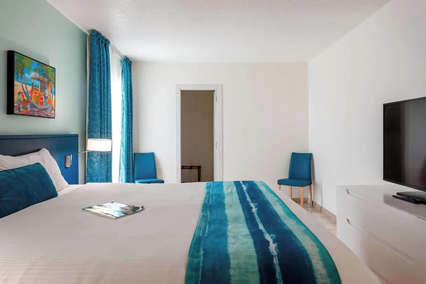 King bed room with blue headboard and wall-mounted TV at Royal Islander Resort La Plage.