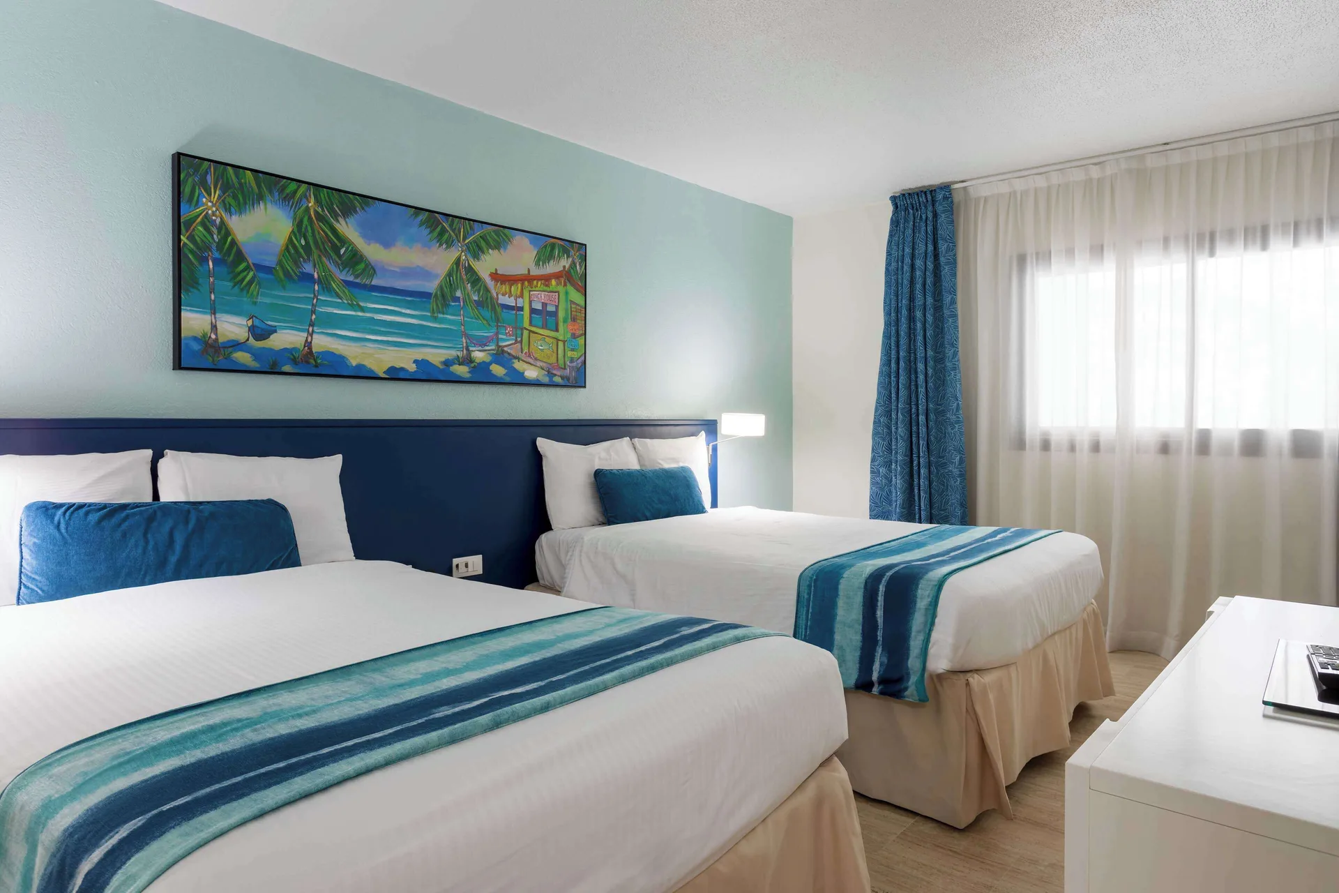 Two double beds with turquoise runners at Royal Islander Resort La Plage.