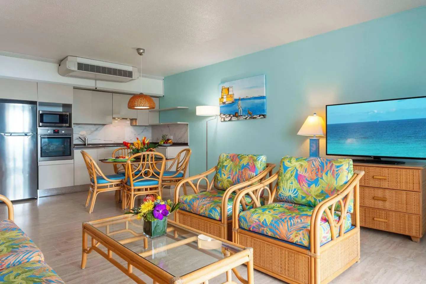 Living room with rattan chairs and open kitchen at Royal Islander Resort La Plage.