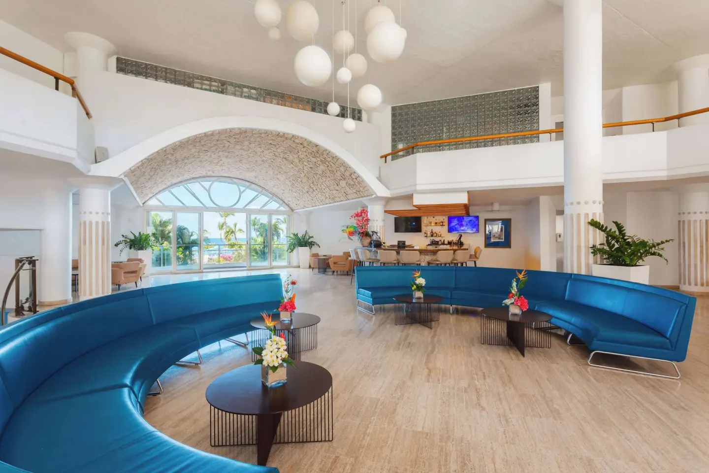 Lobby lounge with blue curved sofas and bar at Royal Islander Resort La Plage.