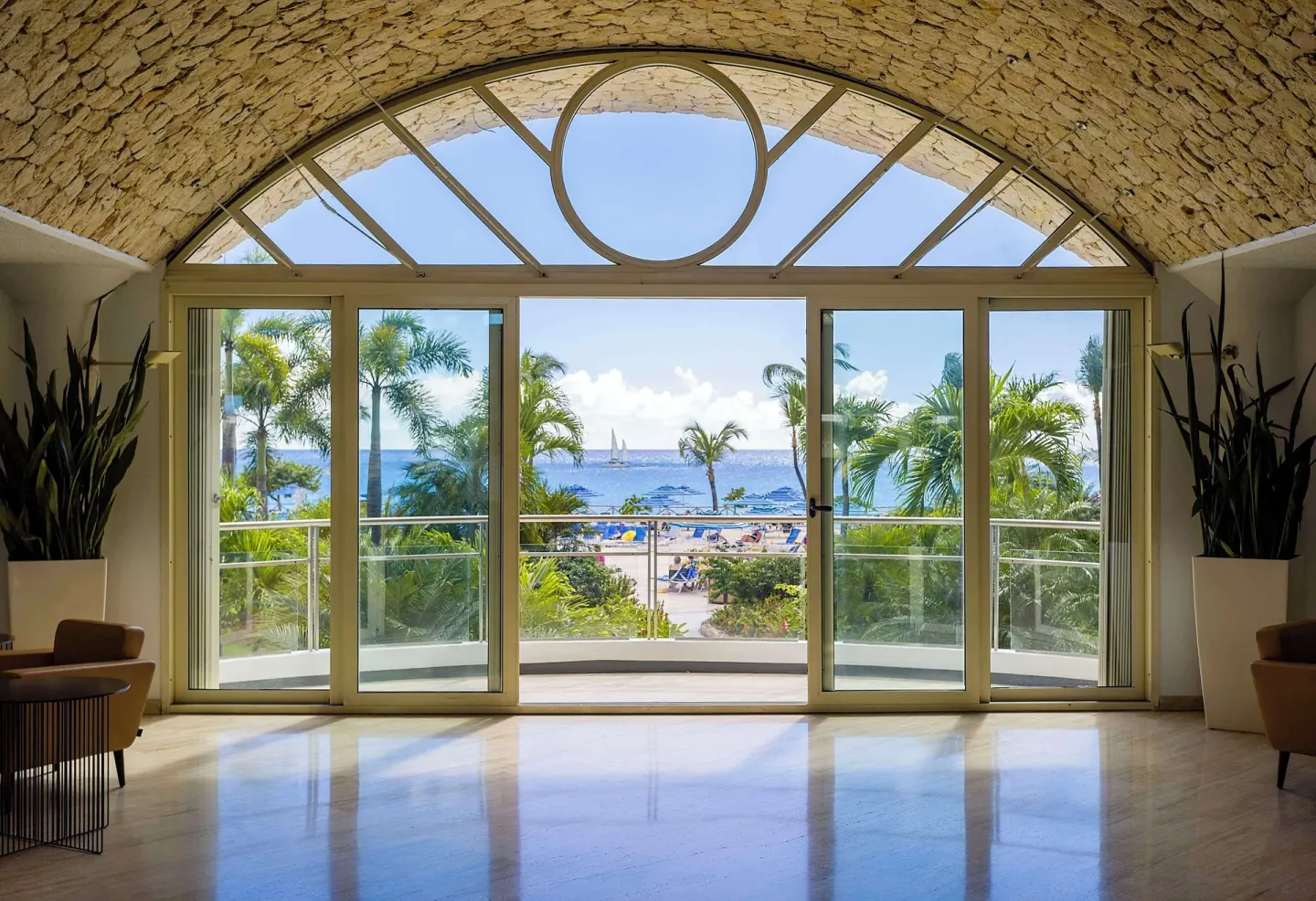 Arched lobby windows overlooking palms and the sea at Royal Islander Resort La Plage.