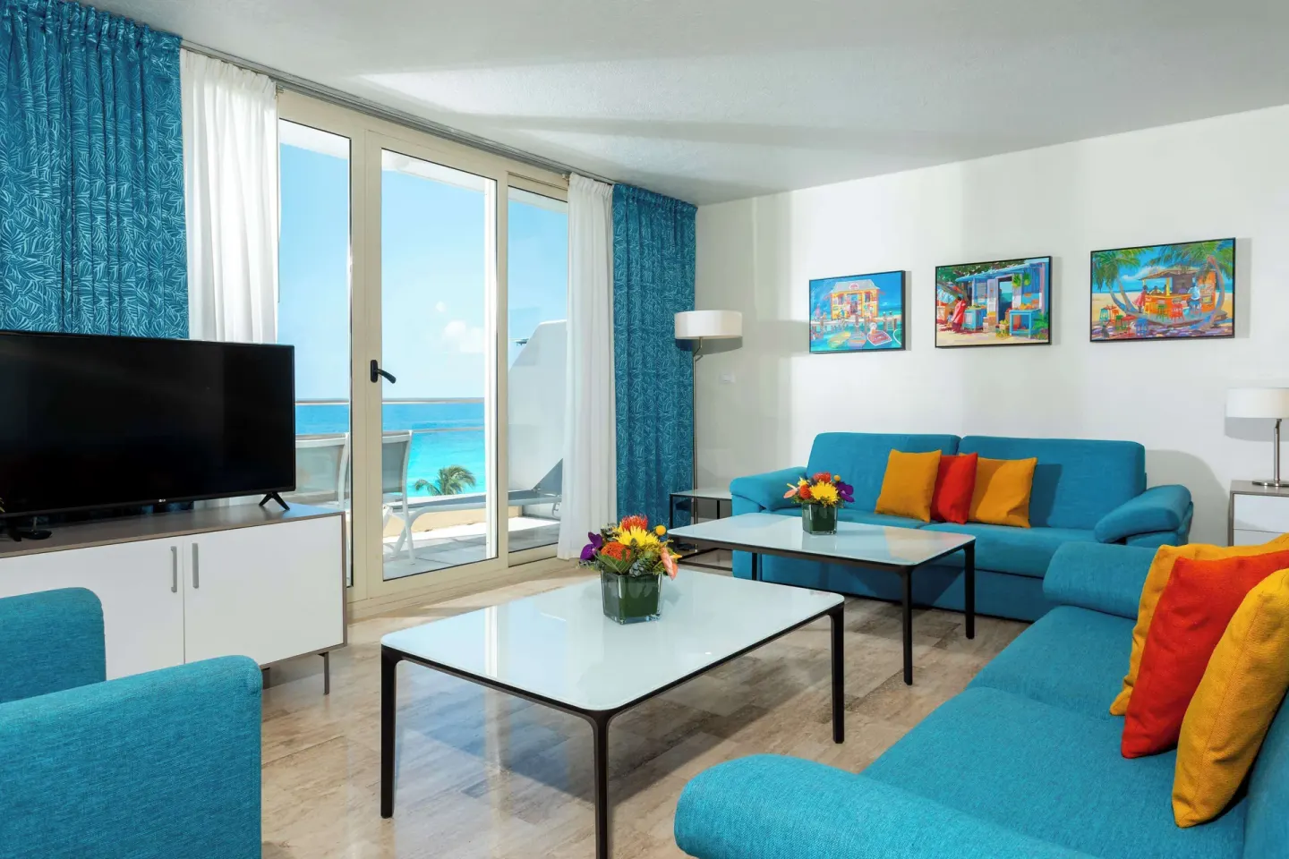 Ocean-view living room with blue seating at Royal Islander Resort La Plage.