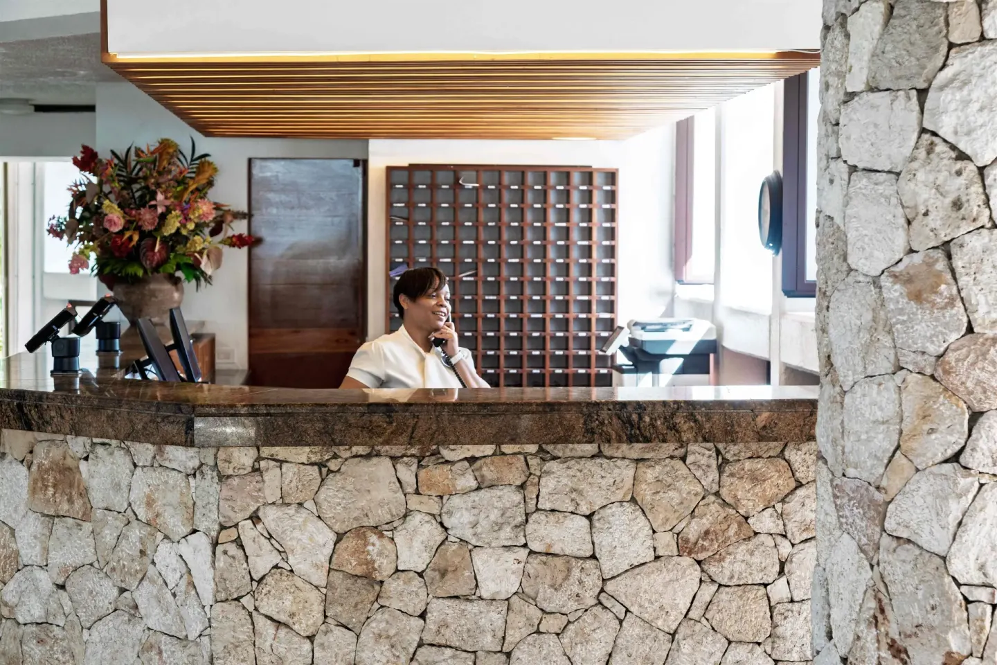 Stone-front reception desk with staff member at Royal Islander Resort La Plage.