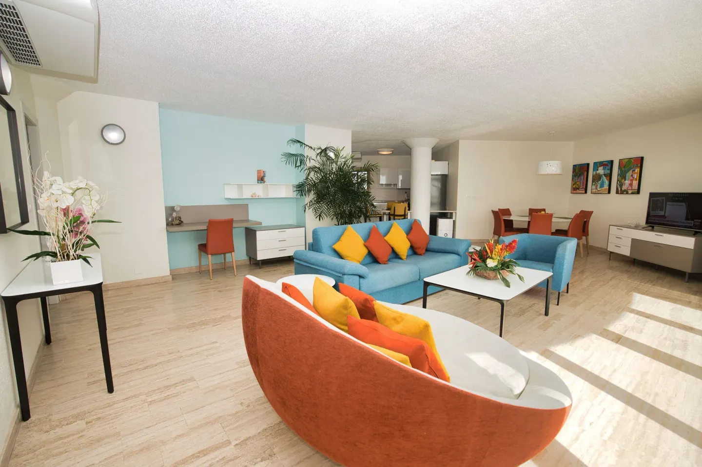 Bright resort living room with colorful sofas and kitchenette at Royal Islander Resort La Plage.