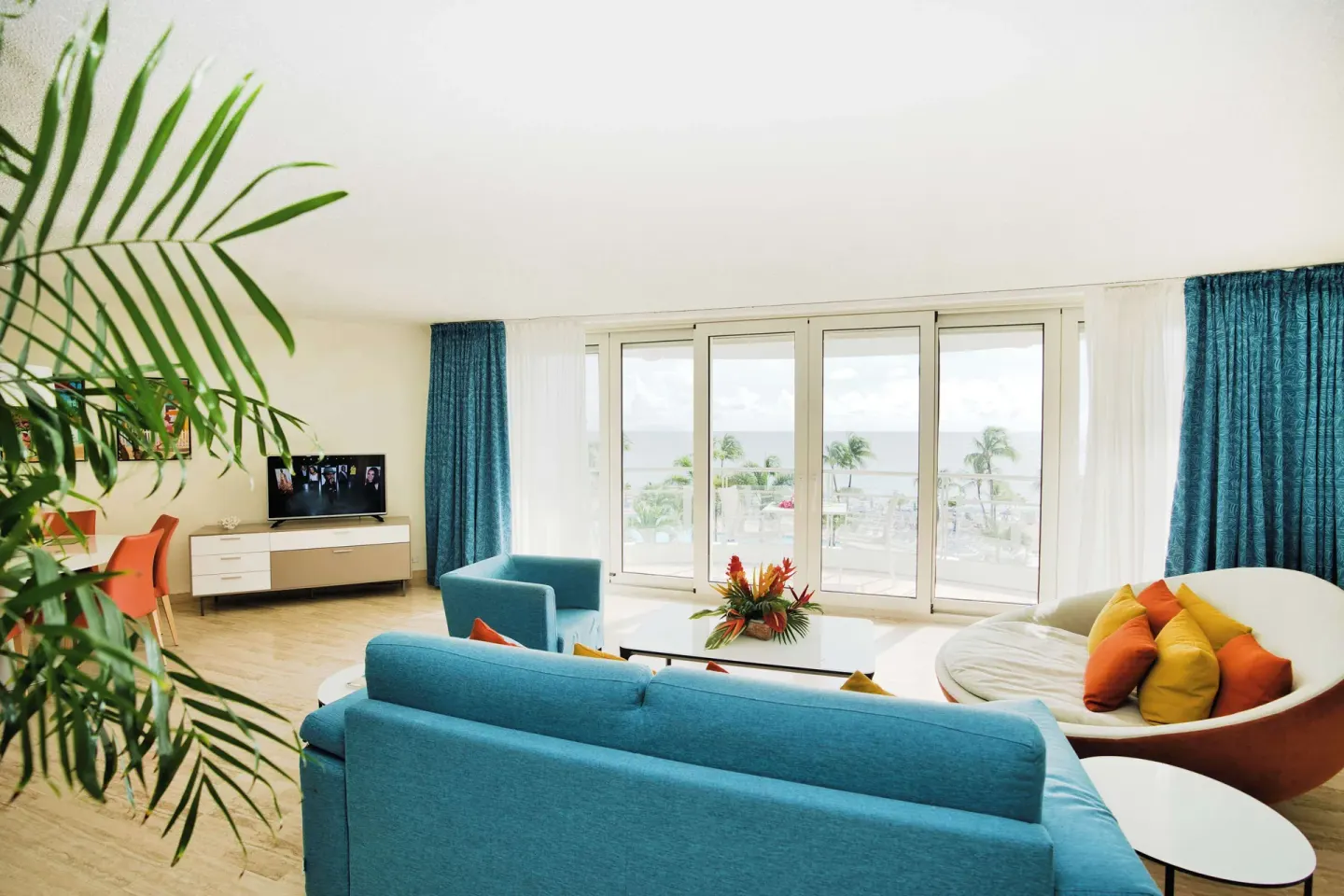 Resort living room with blue sofa and ocean-facing glass doors at Royal Islander Resort La Plage.