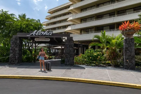Entrance sign and resort tower with guest arriving at Royal Kona Resort.
