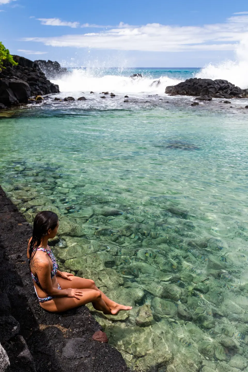 A guest sits beside the clear lava-rock lagoon at Royal Kona Resort.