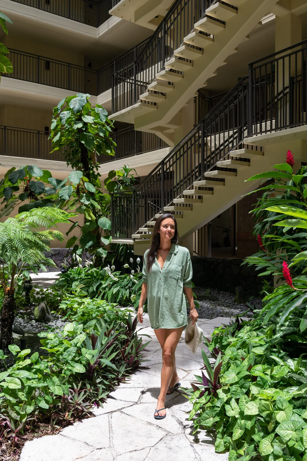A guest walks past tropical plants and open stairways at Royal Kona Resort.