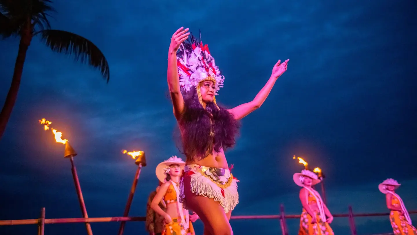 A dancer performs at dusk beside tiki torches at Royal Kona Resort.