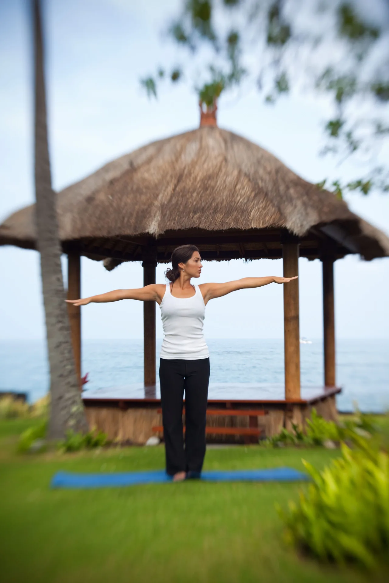 Guest doing yoga on a lawn by a thatched gazebo at Royal Kona Resort.