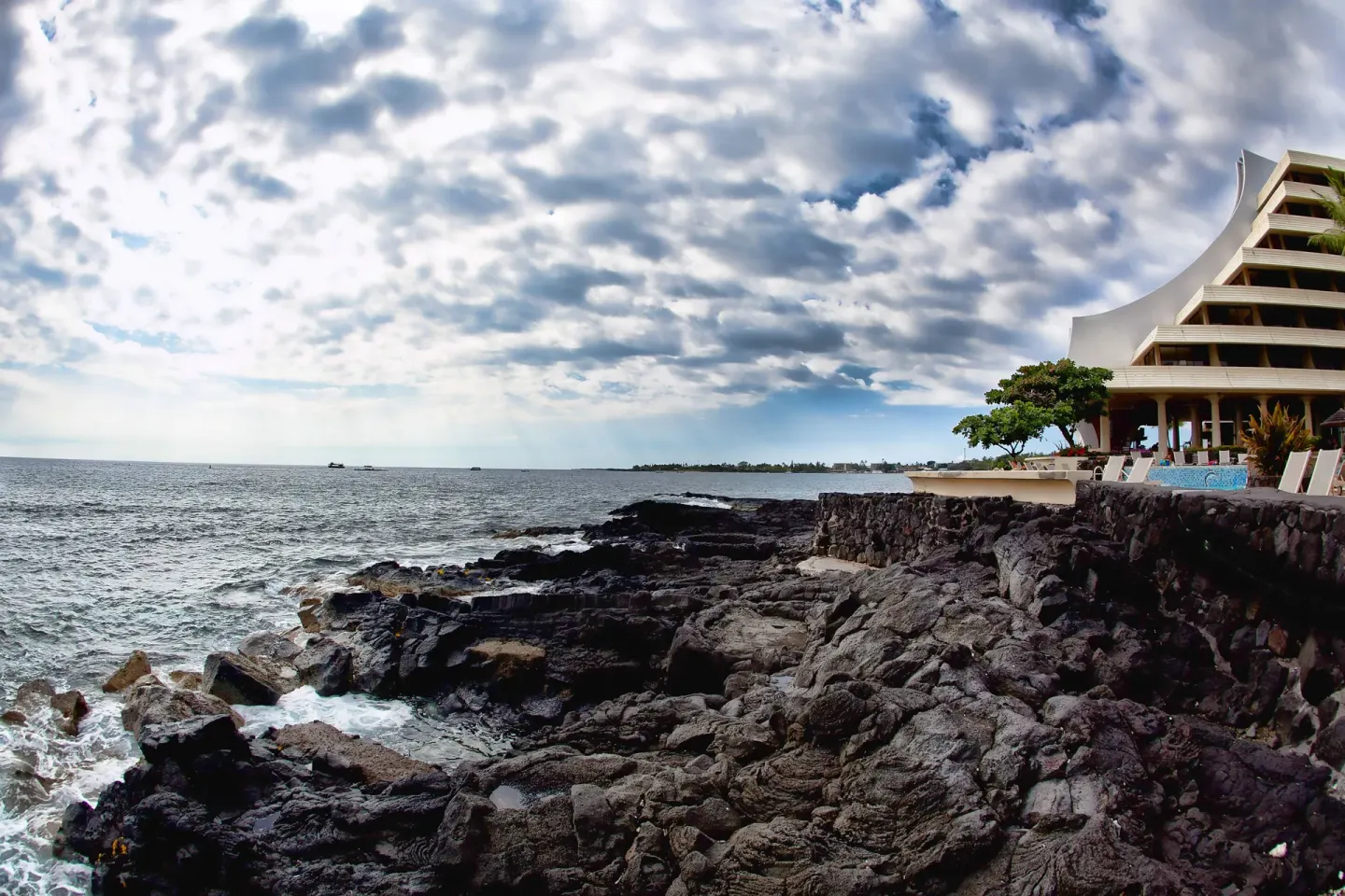Lava-rock shoreline, ocean, and partial resort building at Royal Kona Resort.