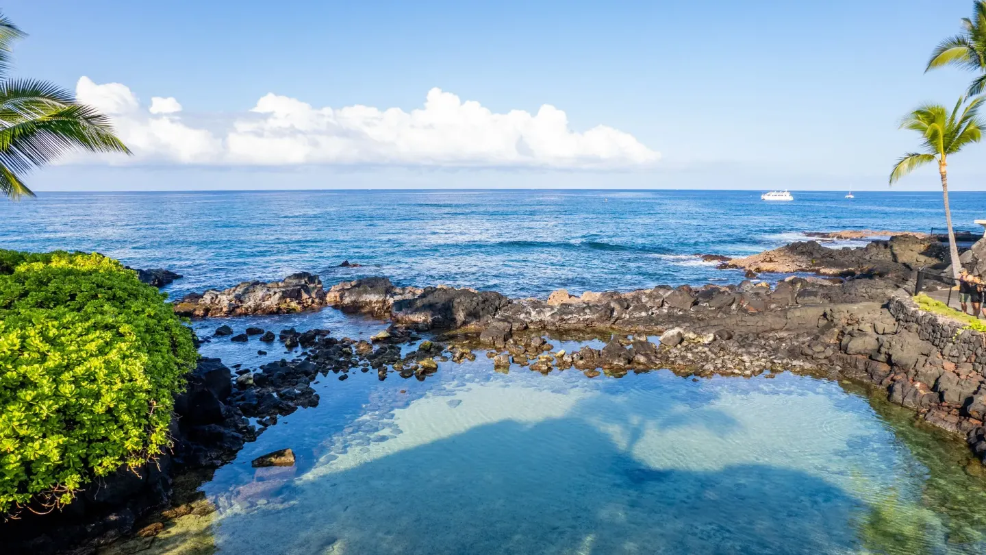 The clear ocean lagoon and lava-rock shoreline are seen at Royal Kona Resort.