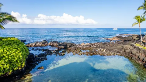 The clear ocean lagoon and lava-rock shoreline are seen at Royal Kona Resort.