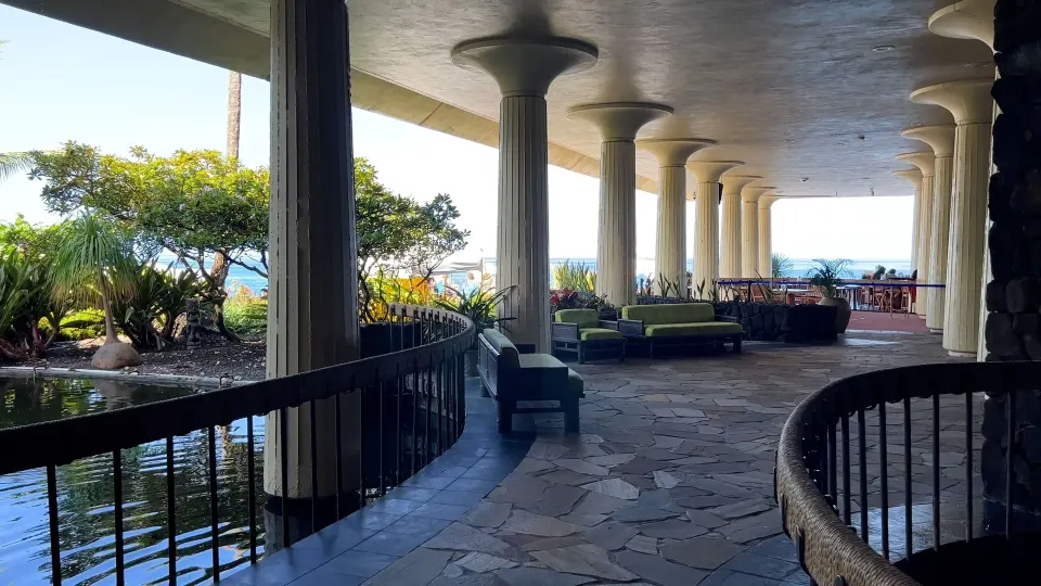 Covered oceanfront walkway with pond and seating at Royal Kona Resort.