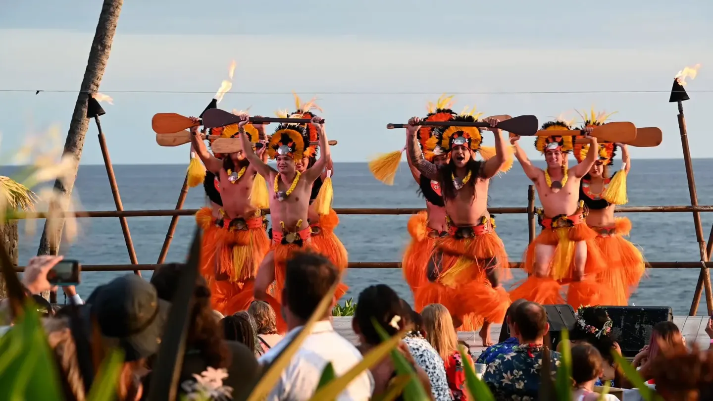 Performers hold paddles on an oceanfront stage at Royal Kona Resort.