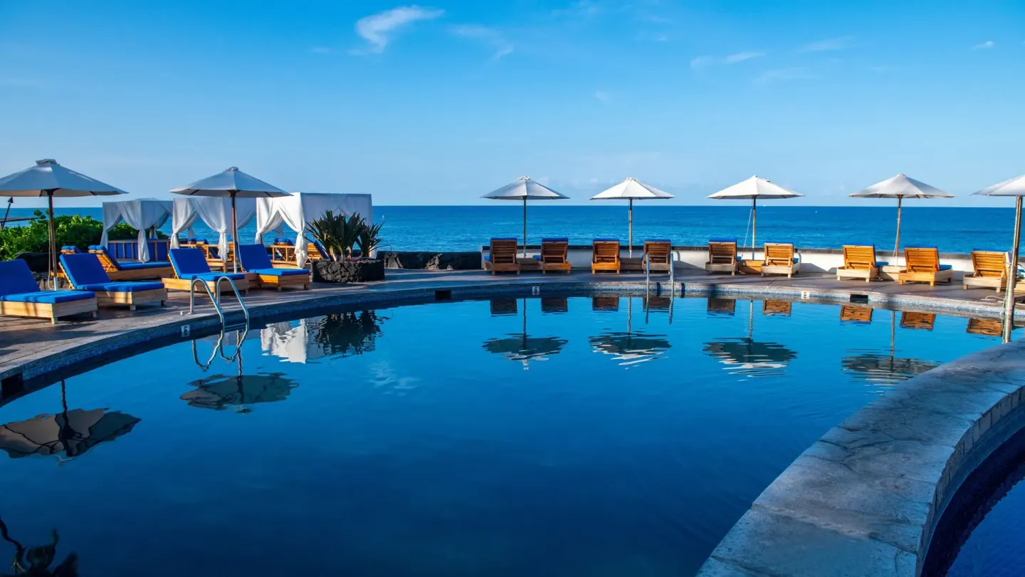 Oceanfront pool with loungers, umbrellas, and cabanas at Royal Kona Resort.