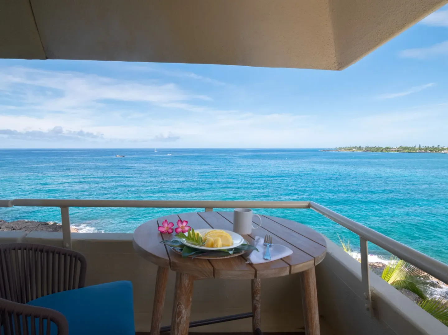 Oceanfront balcony with table setting and blue water view at Royal Kona Resort.