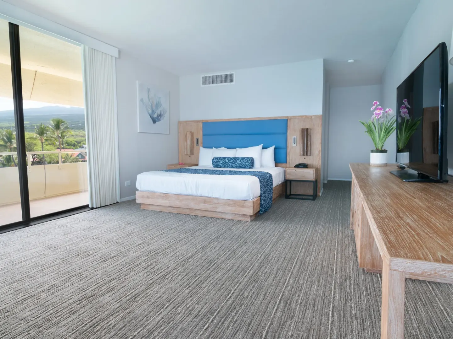 Corner oceanfront guest room with king bed and balcony view at Royal Kona Resort.