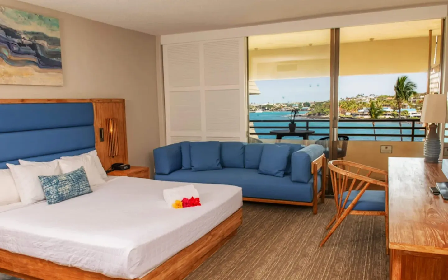 Ocean View room with king bed, blue sofa, desk and balcony at Royal Kona Resort.