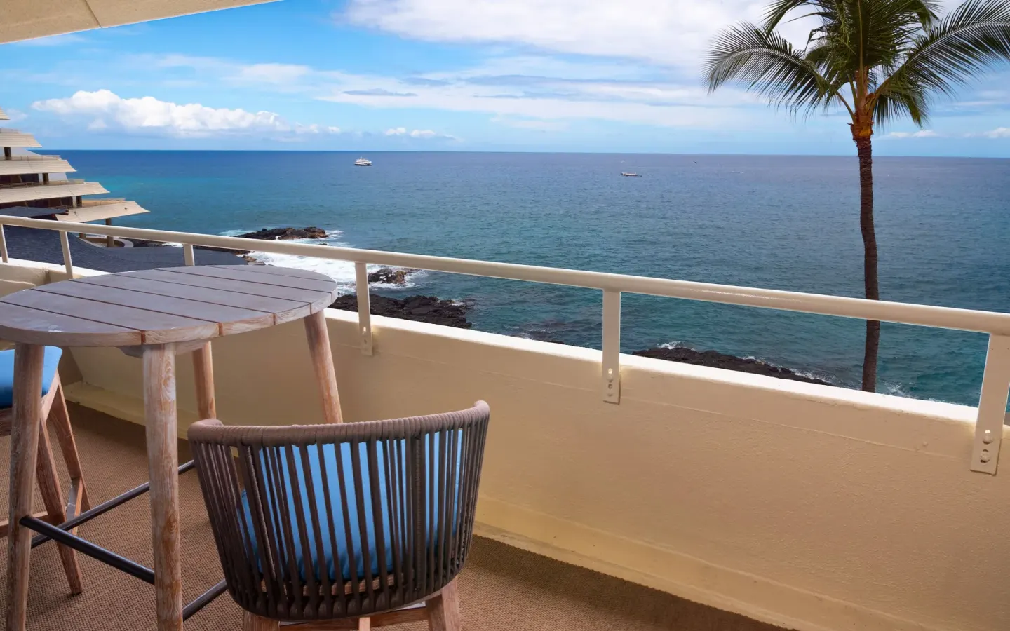 Oceanfront room balcony with table, chair, palm tree, and Pacific view at Royal Kona Resort.