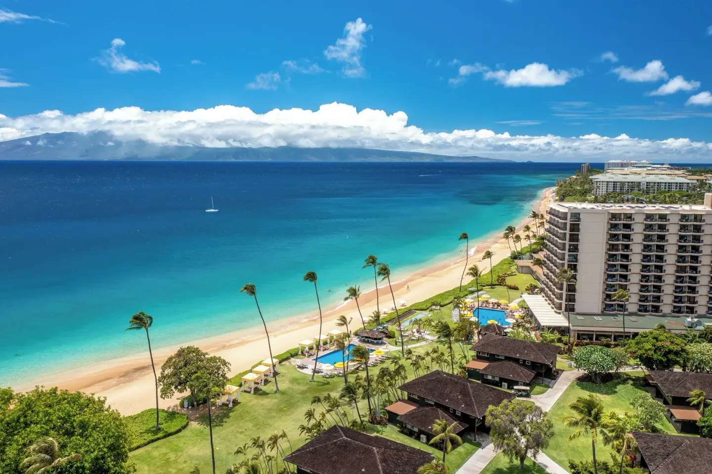 Aerial oceanfront view of Royal Lahaina Resort & Bungalows, beach, pools, and palms.